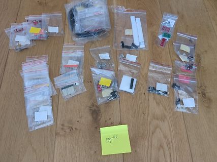 Verschiedene Kleinteile in Plastikbeuteln auf Holzboden