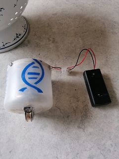 Batteriebetriebener Aufbau mit weißem Gehäuse und DNA-Symbol