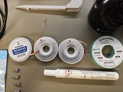 Lötmaterial und Werkzeuge auf Werkstattunterlage
