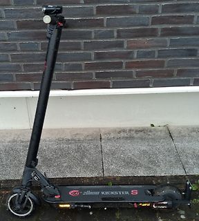 Schwarzer E-Scooter vor einer Ziegelwand