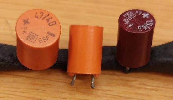 Drei zylindrische Elektrolytkondensatoren auf Holzuntergrund