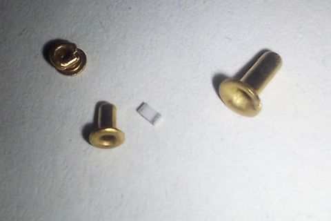 Drei goldfarbene Metallstifte auf weißem Untergrund
