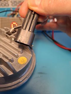 Hand hält elektrischen Stecker an einem Bauteil