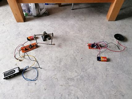 Elektronik-Versuchsaufbau mit Batterien, Platinen und Lautsprecher