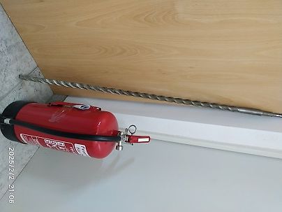 Feuerlöscher und Metallstab auf hellem Untergrund