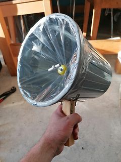 Hand hält einen mit Plastikfolie umwickelten Metalltrichter