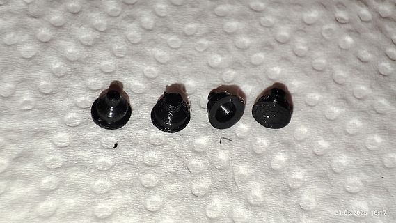 Vier kleine schwarze Bauteile auf weißem Untergrund