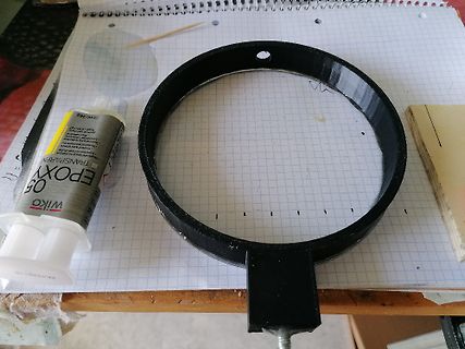 Schwarzer Ring aus Kunststoff, Epoxidharz-Tube und Millimeterpapier