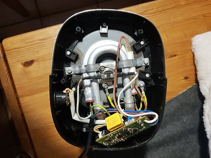 Innenansicht eines geöffneten Elektrogeräts mit Platine und Kabeln