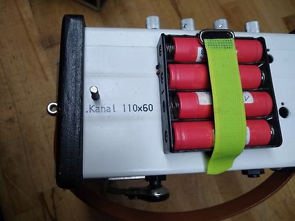 Gehäuse mit vier roten Batterien und grünem Gurt