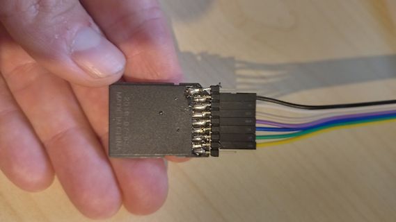 Hand hält Anschlussstecker mit bunten Kabeln