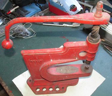 Rote Handpresse auf Werkstatt-Tisch