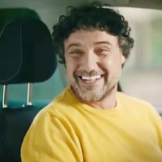 lächelnder Mann in gelbem T-Shirt im Auto