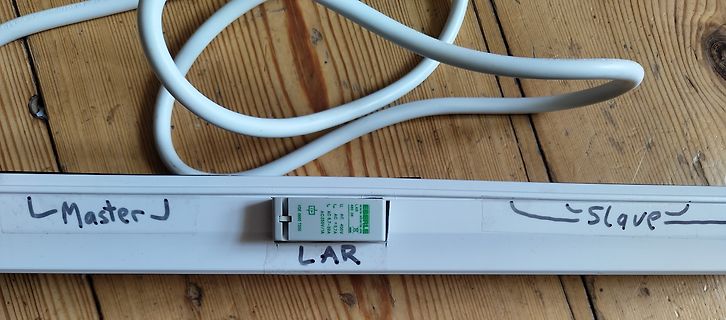 Weißes Gehäuse mit Kabel und Beschriftung auf Holz
