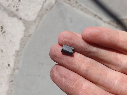 Kleines schwarzes Bauteil in einer Hand