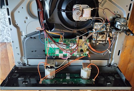 Innenansicht eines geöffneten Elektrogeräts mit Platine und Lüfter