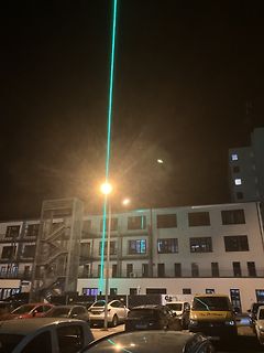 Nachtaufnahme eines Gebäudes mit grünem Laserstrahl