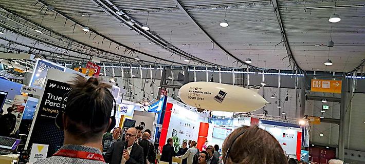 Menschen auf einer Messe mit Werbeaufhängungen