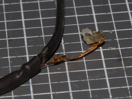 Beschädigtes Kabel mit freiliegender Litze und Bauteil