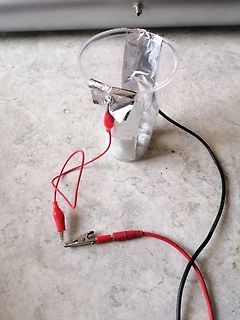 Versuchsaufbau mit Becherglas, Alufolie und Krokodilklemmen