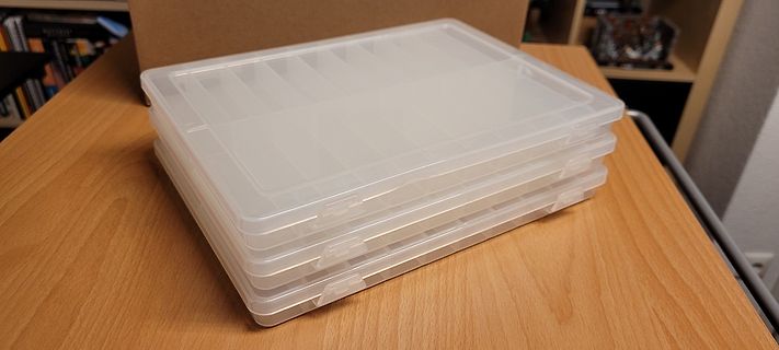 Stapel transparenter Kunststoffboxen auf einem Holztisch