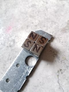 Vier kleine Metallwürfel mit Buchstaben auf Metallstreifen