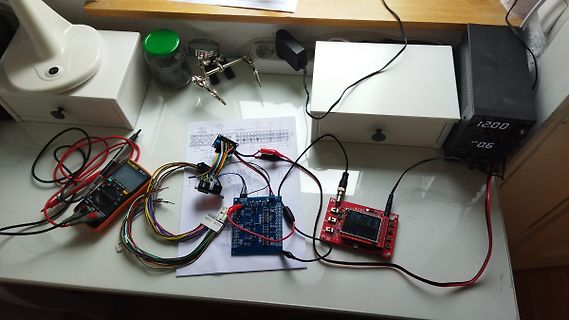Elektronik-Versuchsaufbau mit Multimeter, Platine und Netzteil
