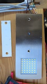 Metallplatte mit LED-Matrix und Kabeln auf Holzuntergrund