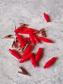Rote Krokodilklemmen auf hellem Untergrund