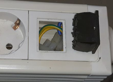 Defekte Steckdose mit freiliegenden Kabeln
