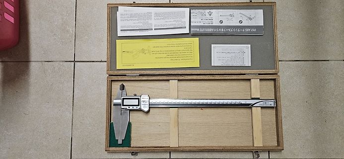 Messschieber in Holzkiste mit Dokumenten