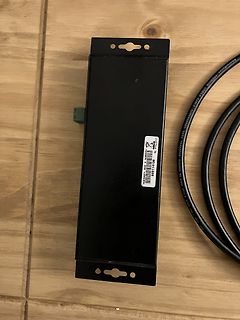 Schwarzes Metallgehäuse mit USB-Kabel auf Holzuntergrund