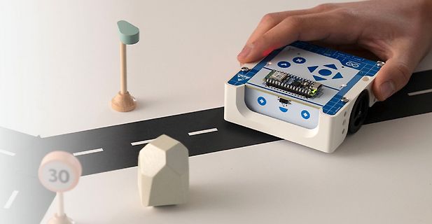Miniatur-Roboter auf Modellstraße mit Straßenschild und Haus