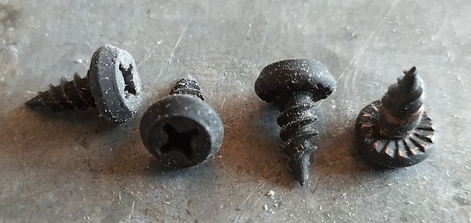 Vier schwarze Schrauben auf Metalloberfläche