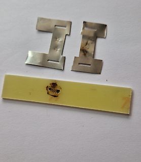 Zwei Metallklammern und ein gelber Streifen mit Brandspuren
