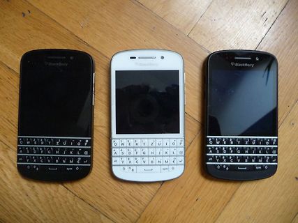 Drei BlackBerry Smartphones auf Holzuntergrund