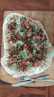 Fladenbrot mit Pilzen und Frühlingszwiebeln auf Holzbrett