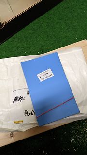 Blaues Buch auf weißem Papier und Holzbrett