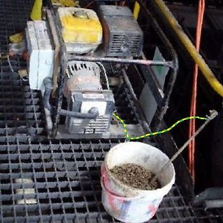 Generator und Eimer mit Material auf Gitterrost