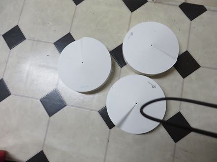 Drei weiße runde TP-Link Geräte auf Fliesenboden