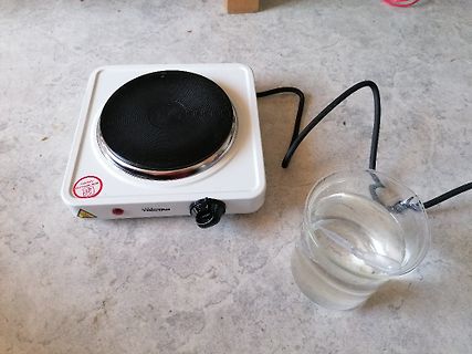 Ein Elektrokochfeld und ein Glas mit Wasser