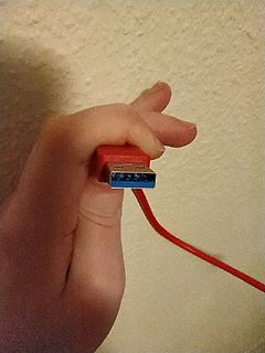 Hand hält rotes USB-Kabel