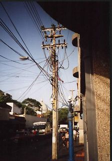 Strommast mit vielen Kabeln in einer Straße
