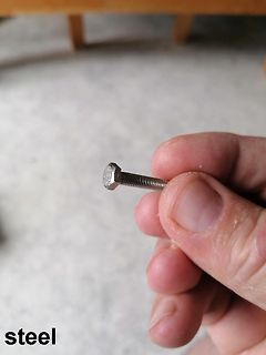 Hand hält eine Stahlschraube