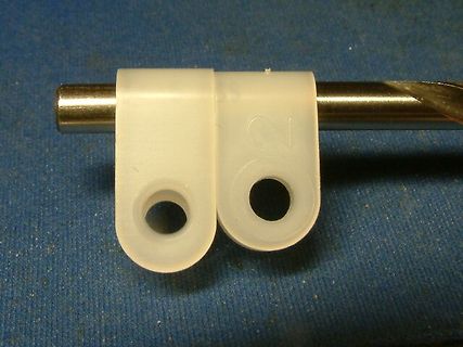 Zwei weiße Kunststoffteile auf einem Metallstab