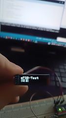 Hand hält Display mit Text vor Laptop