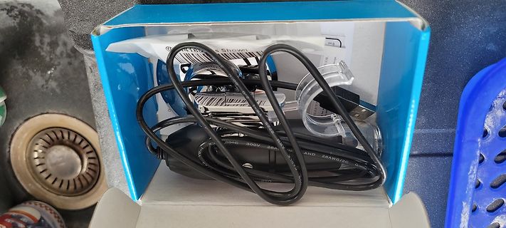 Netzteil und Kabel in einer blauen Schachtel