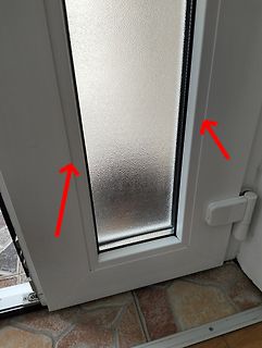 Weiße Tür mit Glasausschnitt und roten Pfeilen