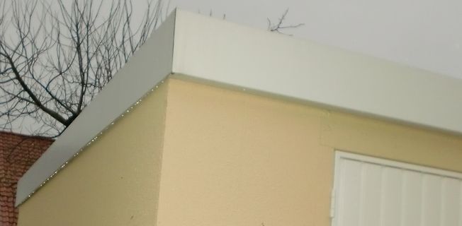 Ecke eines Gebäudes mit Dachkante und Baumzweigen