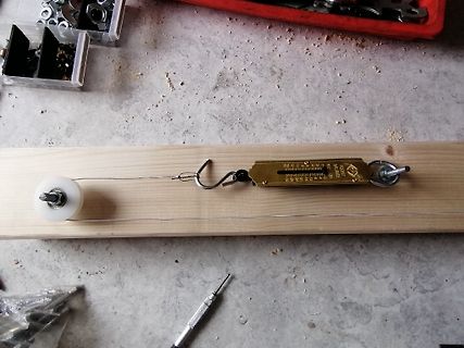 Federwaage an Holzbrett mit Rolle und Draht